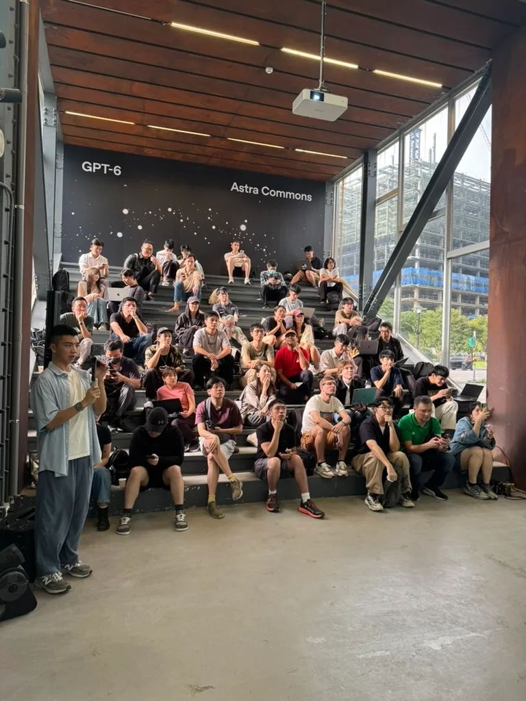 A speaker addresses attendees seated on tiered steps beneath an Astra Commons banner